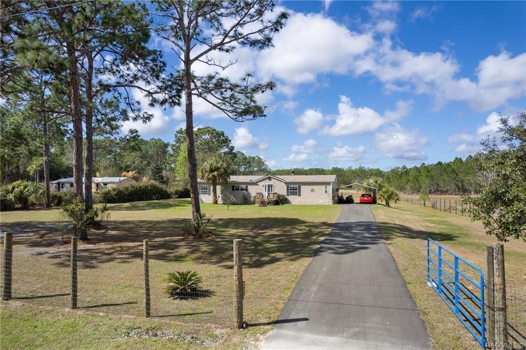 A single-story house with a paved driveway and carport sits on a large grassy lot — 2430 S WAKULLA POINT, HOMOSASSA, FL