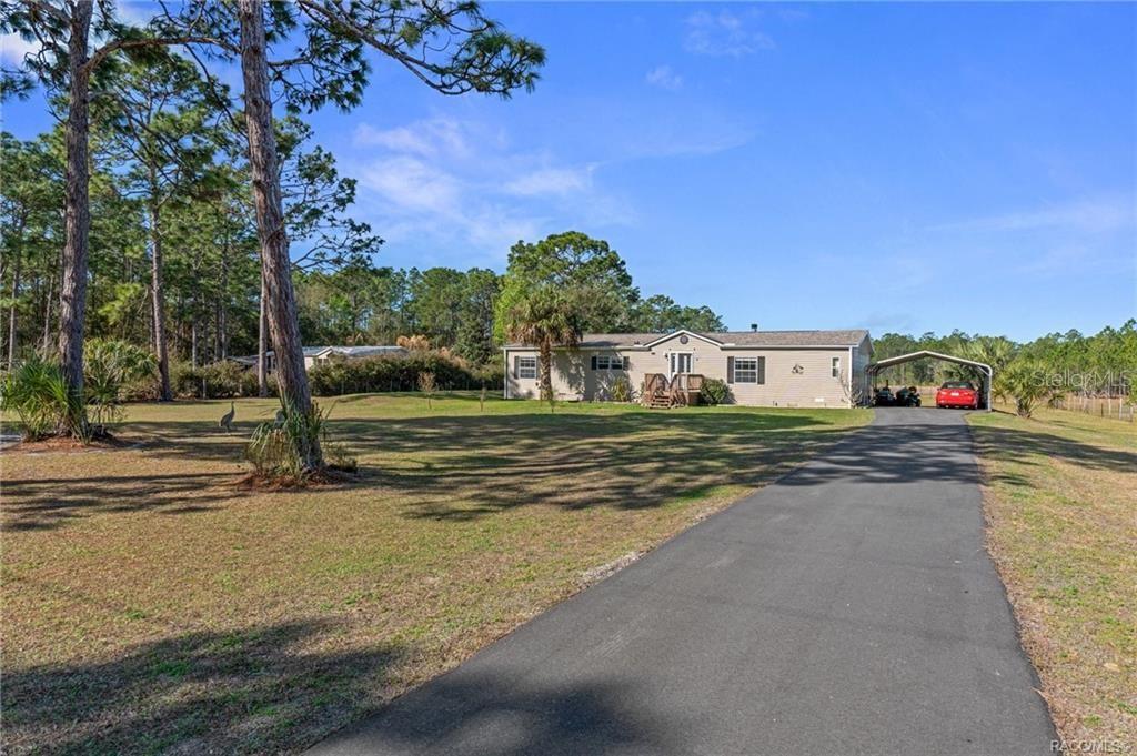 A single-story house with a driveway and carport sits on a large, grassy lot — 2430 S WAKULLA POINT, HOMOSASSA, FL