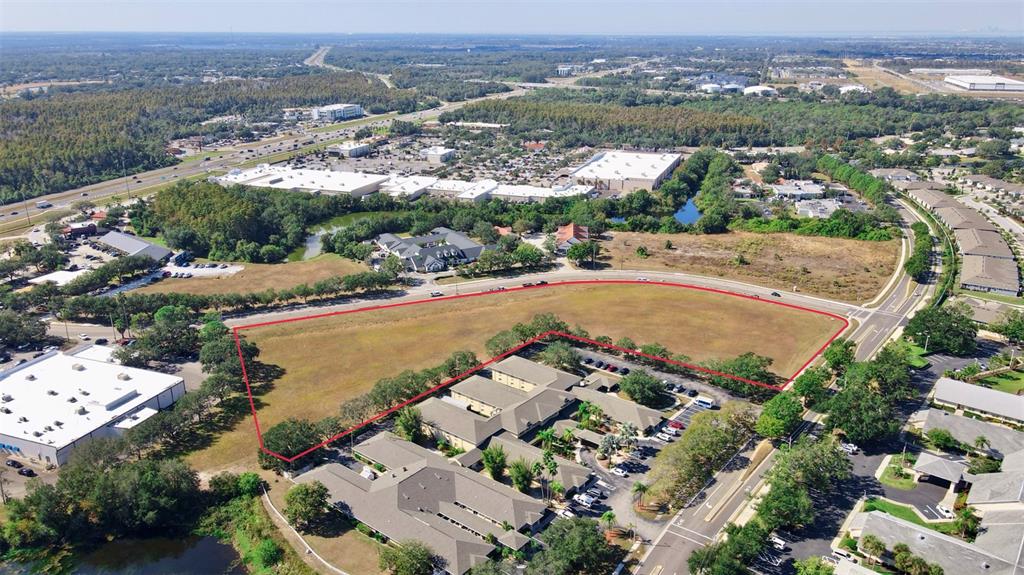 An aerial view shows a vacant, grass-covered lot outlined in red next to commercial buildings — CORTARO DRIVE, SUN CITY CENTER,, FL