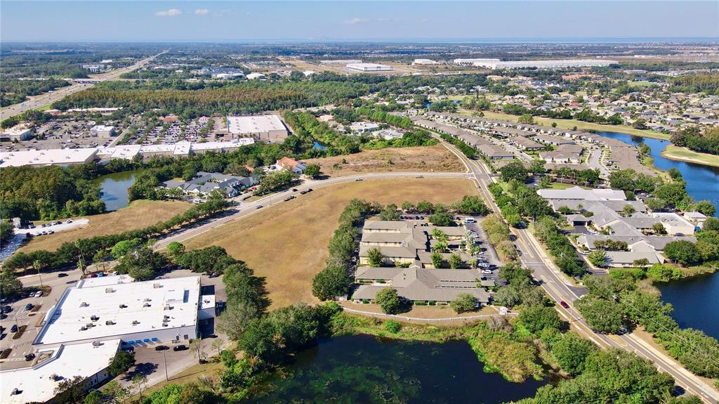 An aerial view shows commercial buildings, residential complexes, and a pond in a suburban area — CORTARO DRIVE, SUN CITY CENTER,, FL