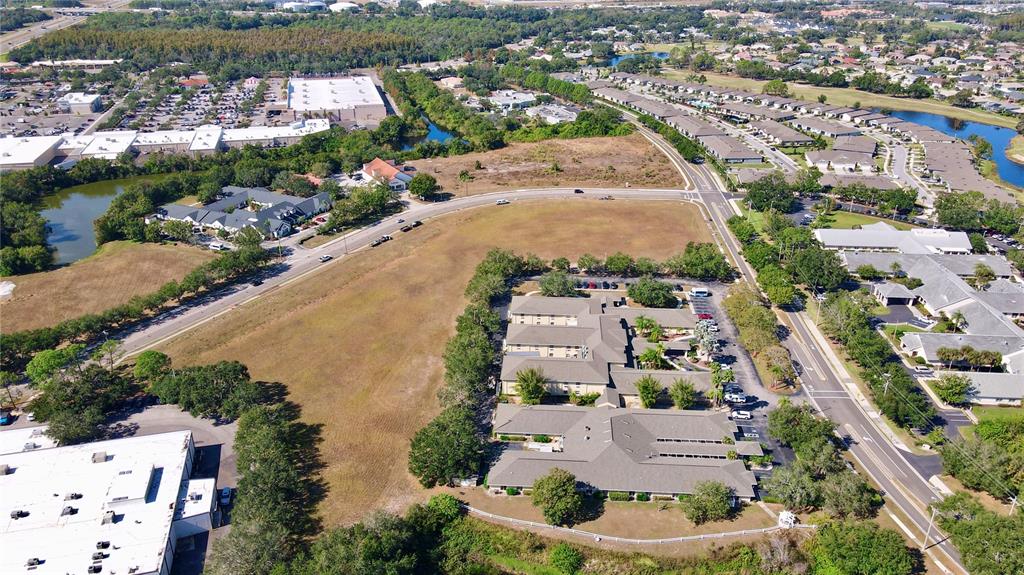 An aerial view shows a commercial building complex surrounded by parking lots and grassy fields — CORTARO DRIVE, SUN CITY CENTER,, FL