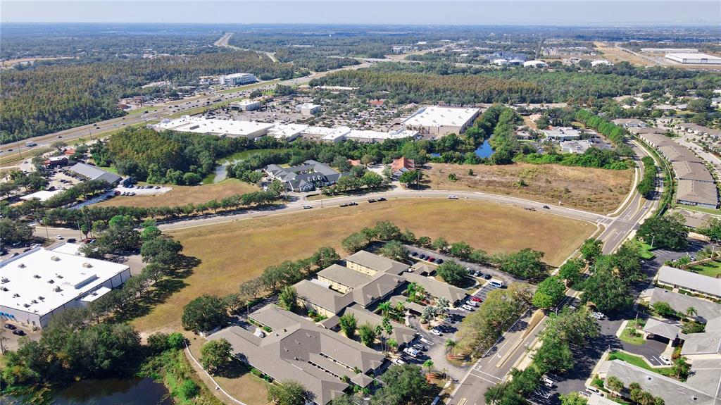This aerial view shows a commercial complex with parking lots, surrounding greenery, and nearby roads — CORTARO DRIVE, SUN CITY CENTER,, FL