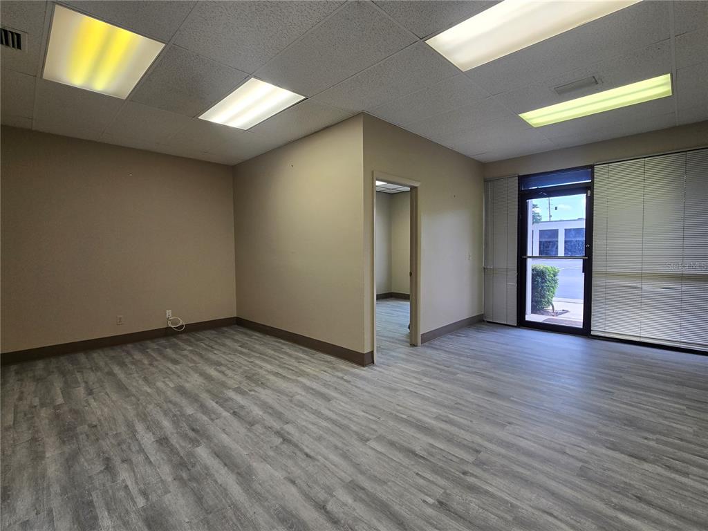 An empty office space features gray wood-look flooring, beige walls, drop ceilings, and a glass door — 9225 ULMERTON ROAD UNIT N, LARGO, FL