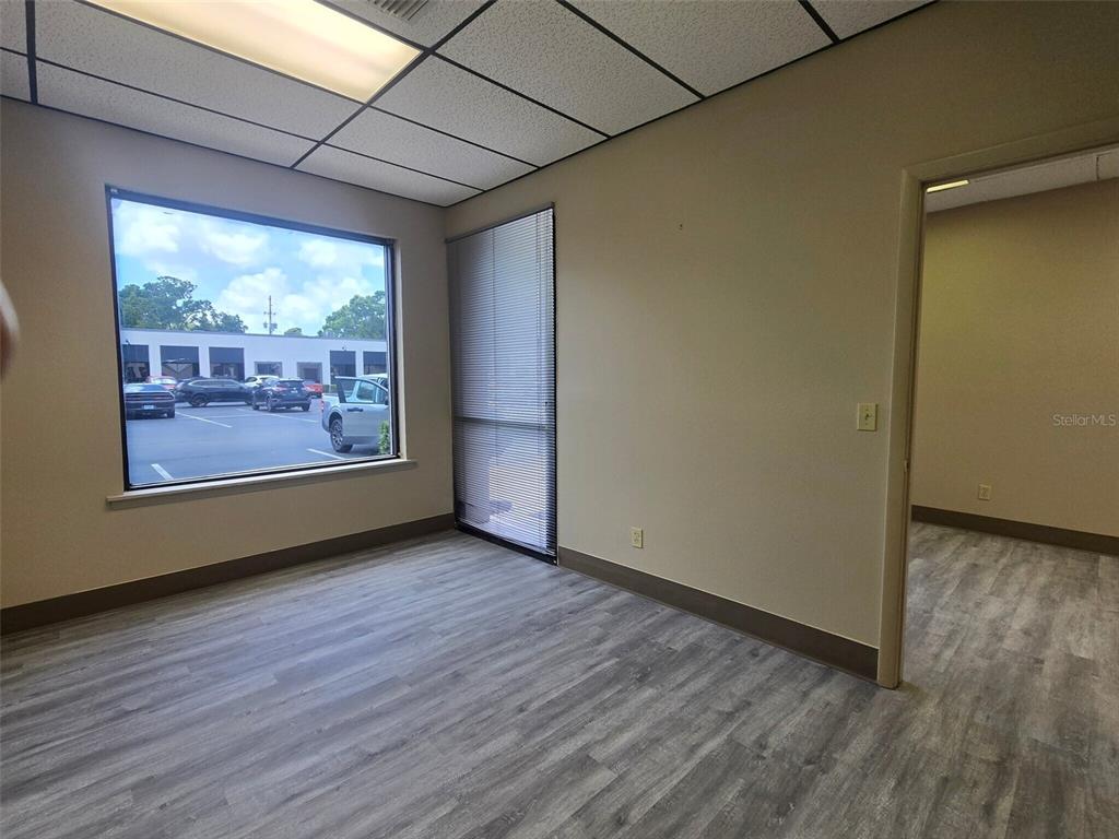 An office room features light wood-look flooring, beige walls, a large window, and recessed lighting — 9225 ULMERTON ROAD UNIT N, LARGO, FL