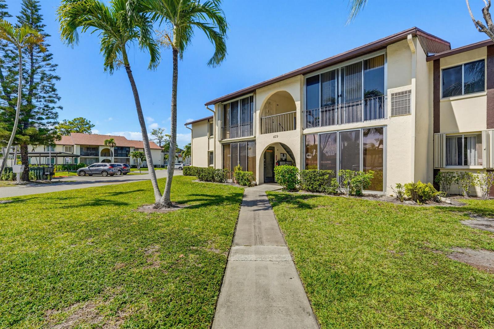 A two-story apartment building with a concrete walkway leading to a central arched entrance — 5760 Pine Wood Drive # 1, FL 33463, FL