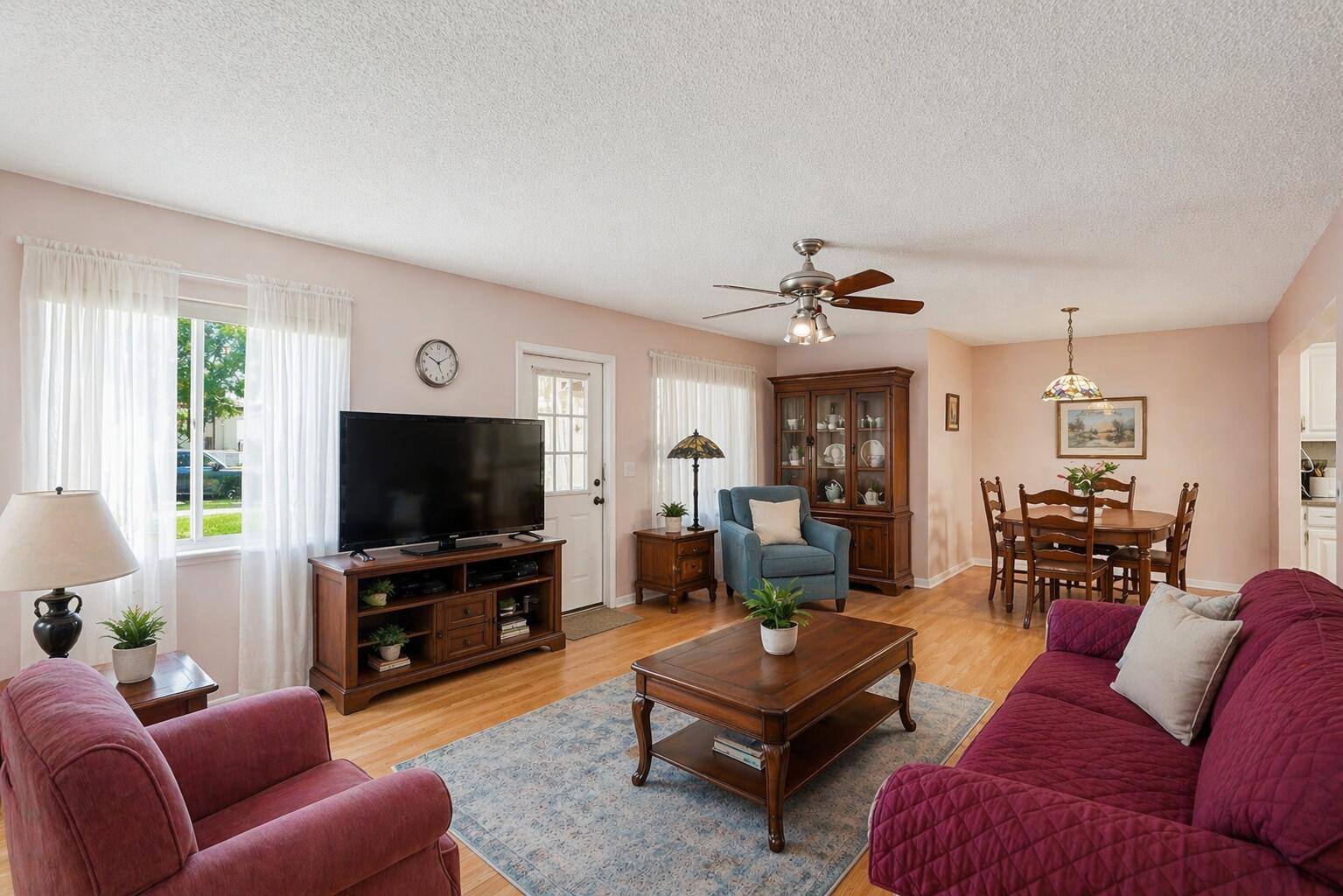 A living room with hardwood floors, a purple sofa, a television, and an adjacent dining area — 5760 Pine Wood Drive # 1, FL 33463, FL