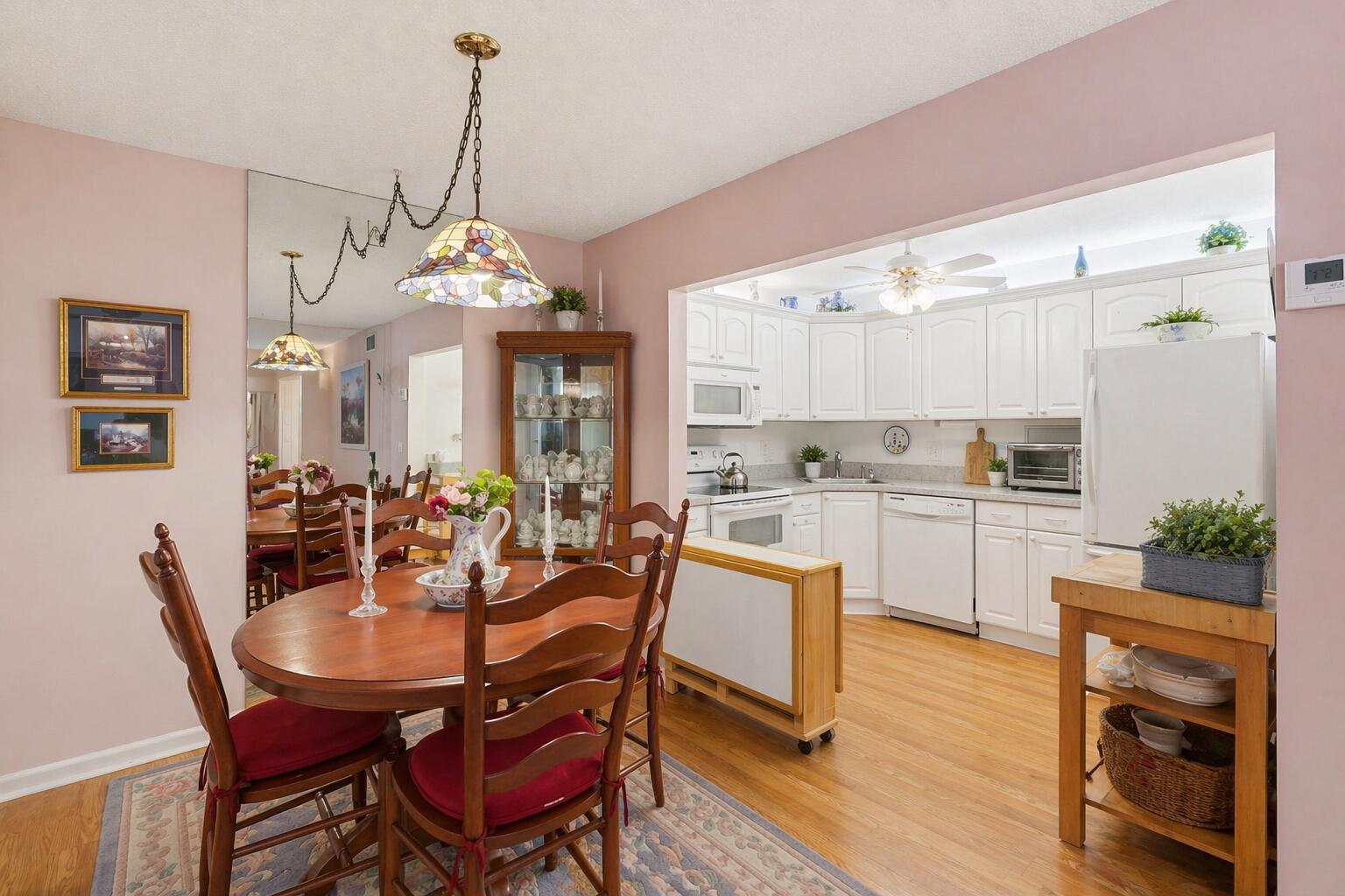 A dining area with a wooden table and chairs sits adjacent to a white kitchen — 5760 Pine Wood Drive # 1, FL 33463, FL