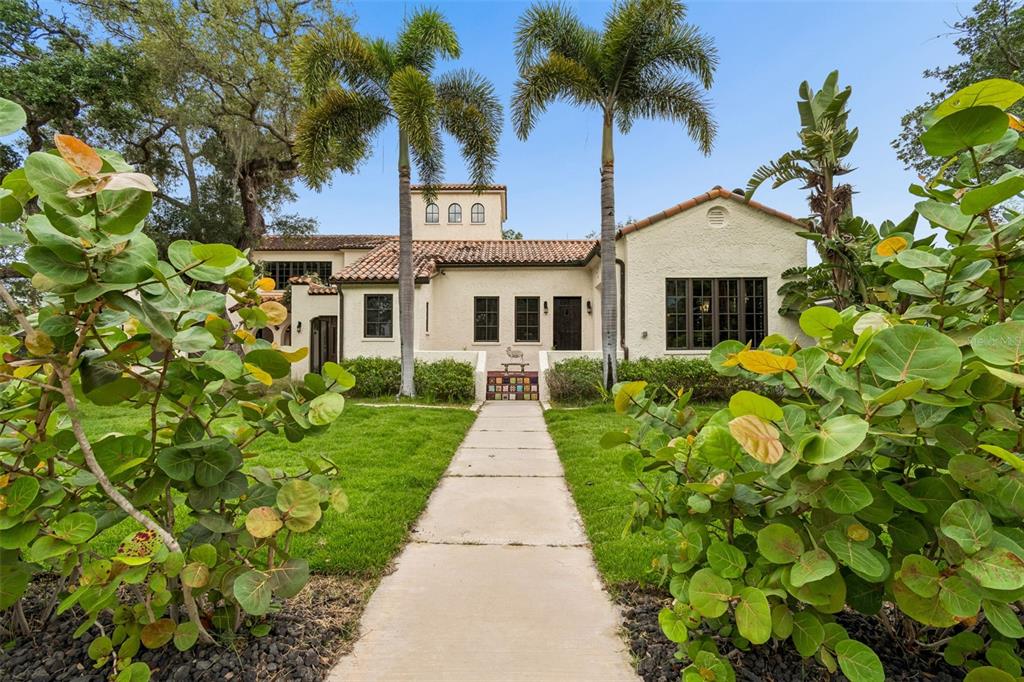 A concrete driveway leads to a Mediterranean-style house surrounded by large trees and palm trees — 2603 S PARKVIEW STREET, TAMPA, FL