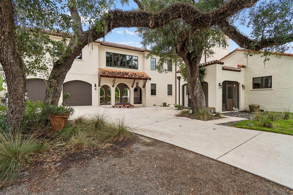 A two-story stucco house with a tile roof, arched entryway, and large oak trees — 2603 S PARKVIEW STREET, TAMPA, FL