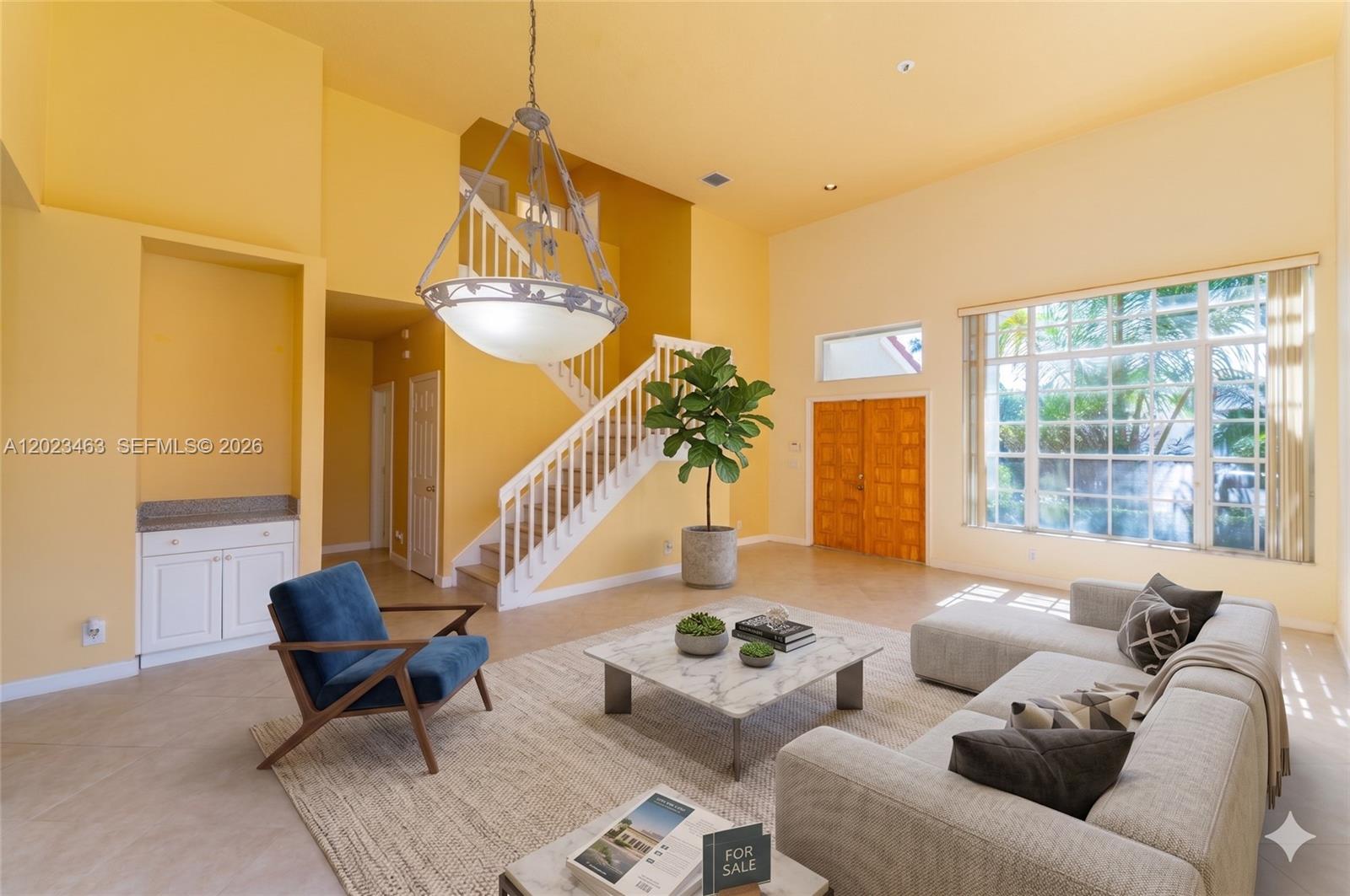A bright living room features high ceilings, a staircase, a large window, and modern furniture — 7131 NW Turtle Walk, Boca Raton FL 33487, BOCA RATON, FL