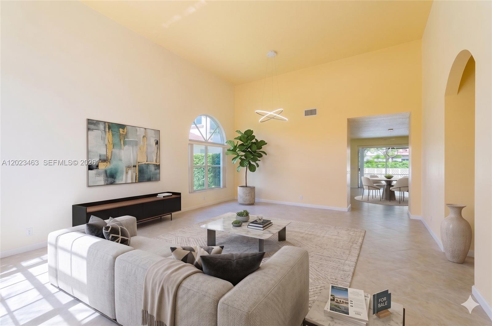 A spacious living room features high ceilings, light yellow walls, a modern sofa, and tile flooring — 7131 NW Turtle Walk, Boca Raton FL 33487, BOCA RATON, FL