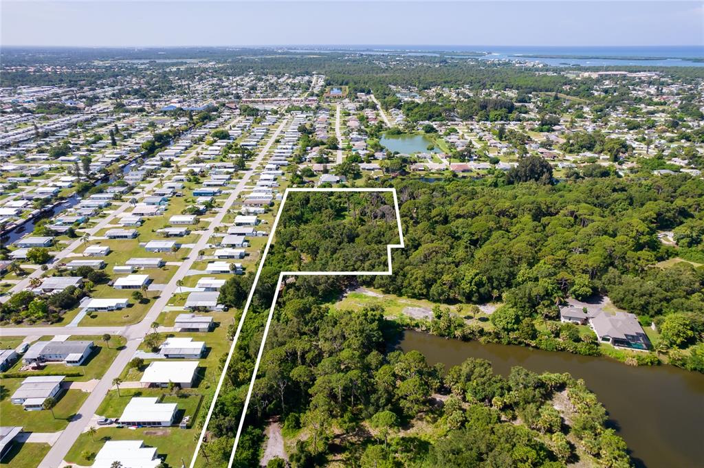 An aerial view shows a wooded lot outlined in white adjacent to a residential neighborhood — 1139 DRURY LANE, ENGLEWOOD, FL