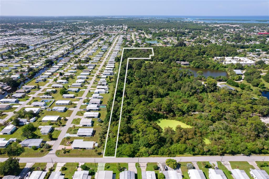 An aerial view shows a vacant, L-shaped wooded lot outlined in white next to a neighborhood — 1139 DRURY LANE, ENGLEWOOD, FL