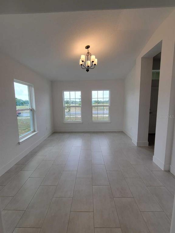 A bright dining area features light-colored tile flooring, a central chandelier, and three large windows — 4392 SW 92ND PLACE ROAD, OCALA, FL