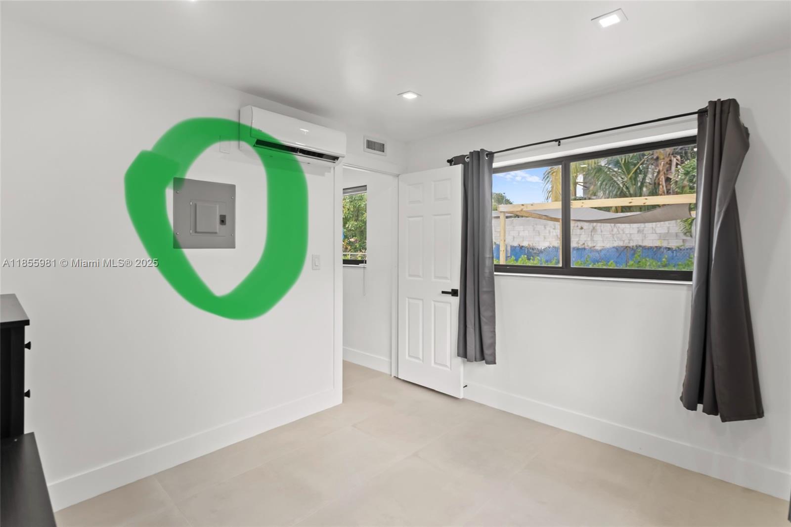 A bedroom features white walls, tile flooring, a window, a mini-split unit, and an electrical panel — 3125 NW 21st Ct # 02, Miami FL 33142, MIAMI, FL