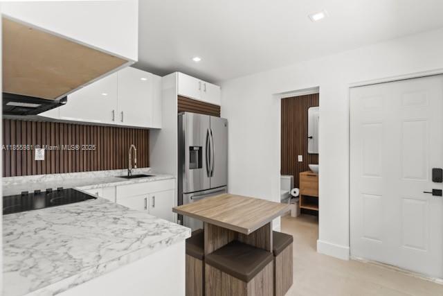 A modern kitchen features white cabinets, marble-patterned countertops, a stainless steel refrigerator, and wood paneling — 3125 NW 21st Ct # 02, Miami FL 33142, MIAMI, FL