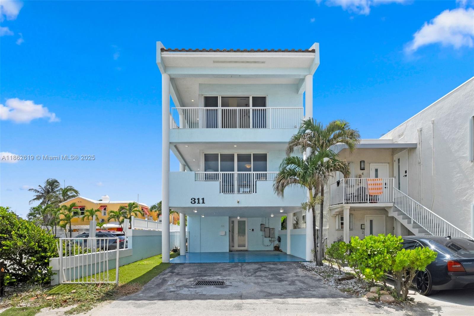 A three-story light blue house features a ground-level carport and two upper balconies — 311 N Surf Rd # 311, Hollywood FL 33019, HOLLYWOOD, FL