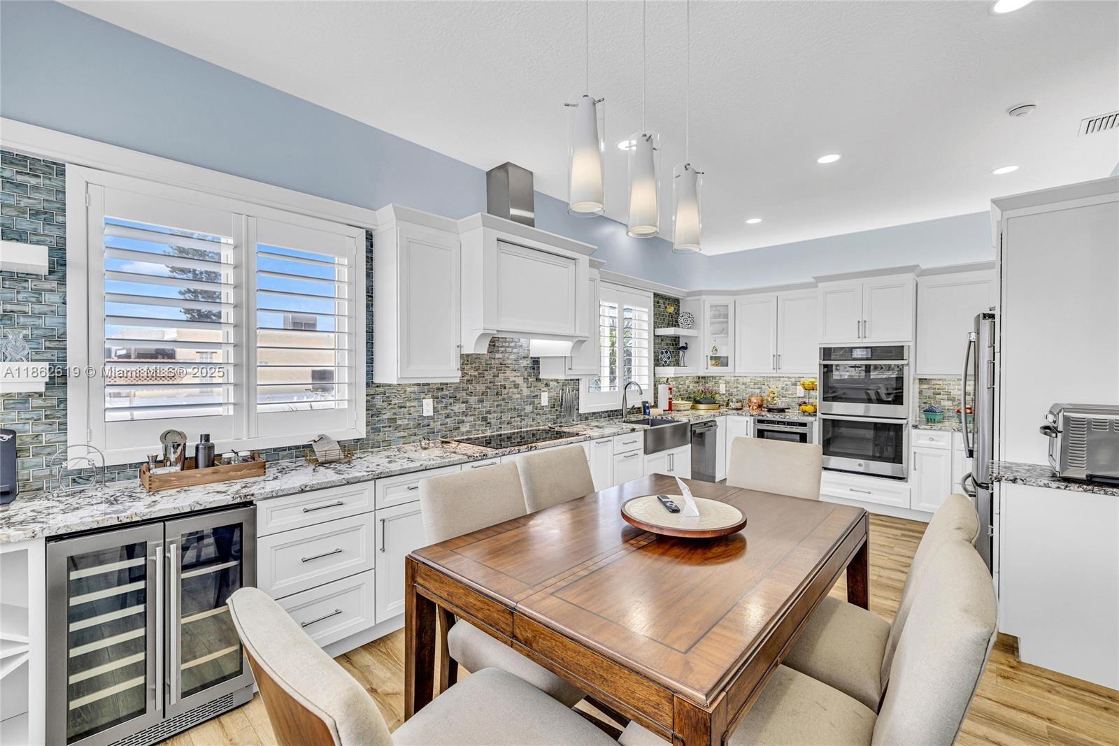 A kitchen features white cabinetry, a wooden dining table, and a blue-tiled backsplash — 311 N Surf Rd # 311, Hollywood FL 33019, HOLLYWOOD, FL