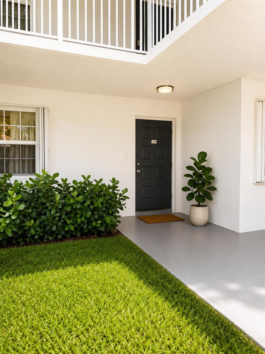 A dark front door with the number 104 sits on a gray porch beside a plant — 4200 Oaks Terrace # 104, Pompano Beach FL 33069, POMPANO BEACH, FL