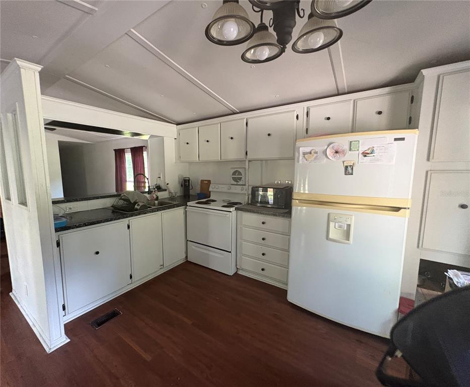 A kitchen with white cabinets, a white stove, a refrigerator, and dark countertops — 15210 NE 144TH STREET, FORT MC COY, FL