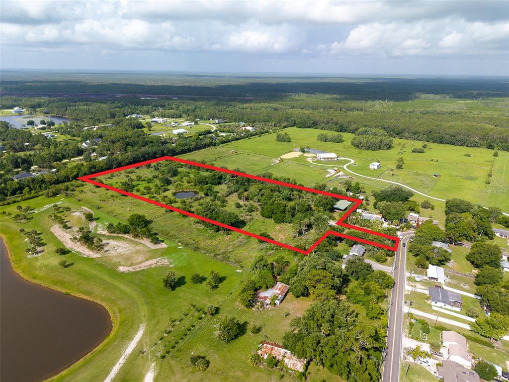 An aerial view shows a large, rectangular plot of land outlined in red near a road — 1405 S GLENCOE ROAD, NEW SMYRNA BEACH, FL
