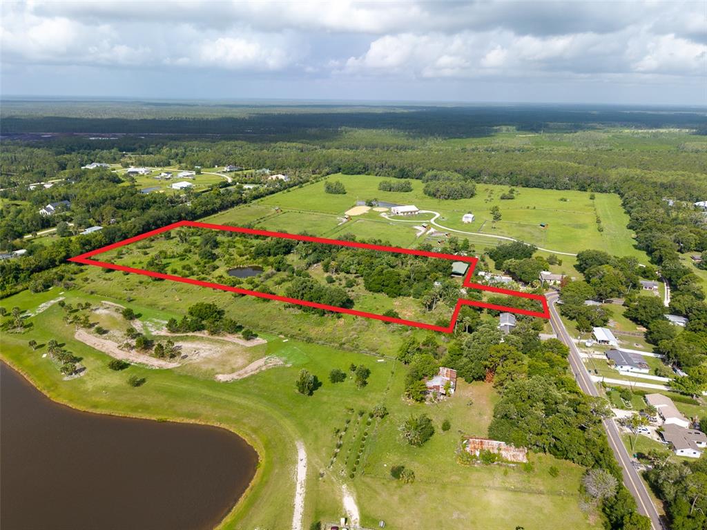 An aerial view shows a large, rectangular plot of land outlined in red near a road — 1405 S GLENCOE ROAD, NEW SMYRNA BEACH, FL