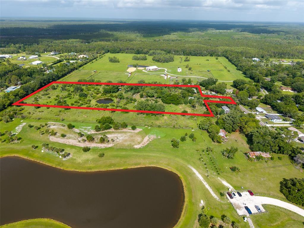An aerial view shows a large, rectangular plot of land outlined in red near a pond — 1405 S GLENCOE ROAD, NEW SMYRNA BEACH, FL