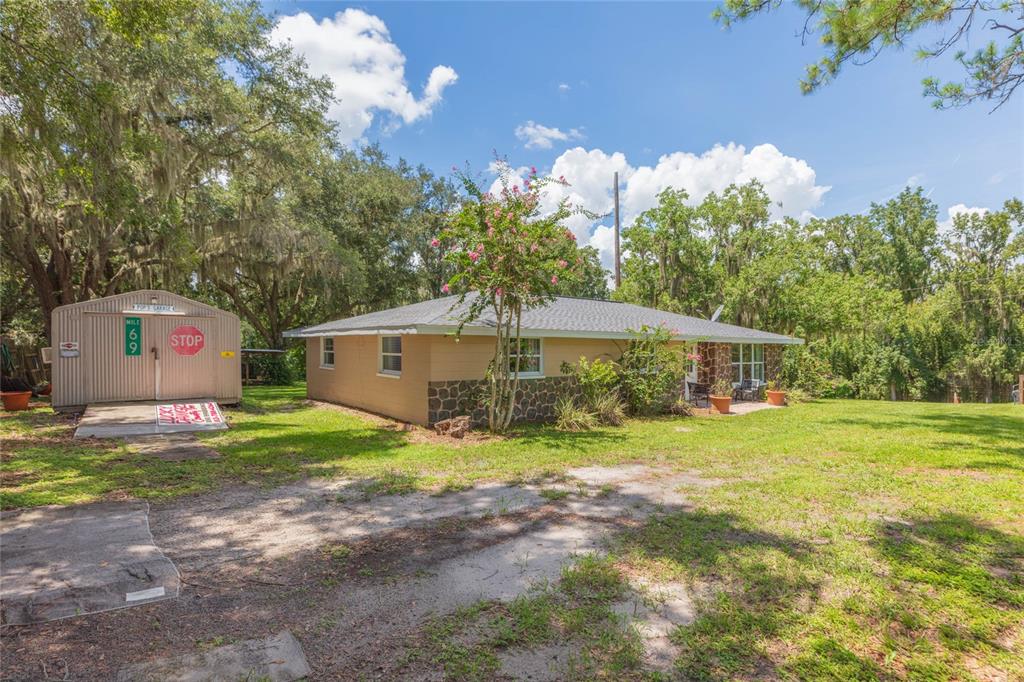 A single-story house with stone accents and a detached metal garage on a grassy lot — 8719 HANDCART ROAD, WESLEY CHAPEL, FL