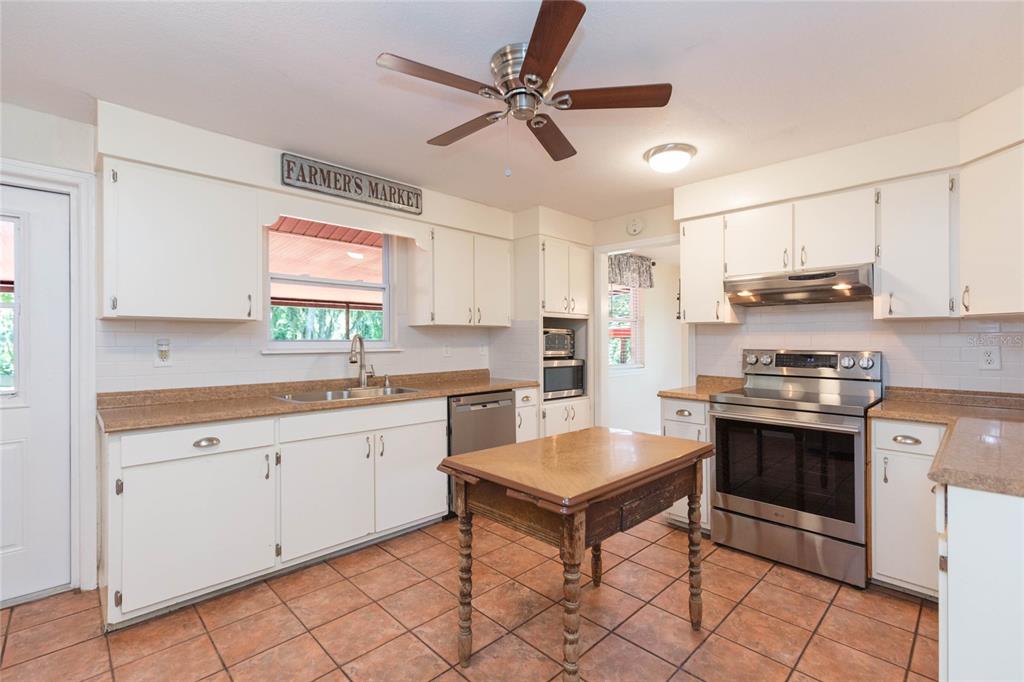 A kitchen with white cabinets, stainless steel appliances, a wooden island, and tiled floors — 8719 HANDCART ROAD, WESLEY CHAPEL, FL