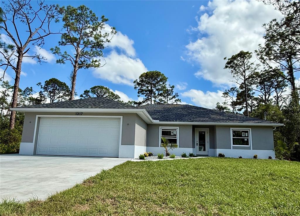 A single-story house with a two-car garage, gray stucco walls, and a dark shingled roof — 1317 BISCAYNE DRIVE, PORT CHARLOTTE, FL