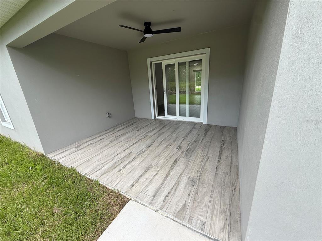 A covered patio features wood-look tile flooring, a ceiling fan, and sliding glass doors — 1317 BISCAYNE DRIVE, PORT CHARLOTTE, FL