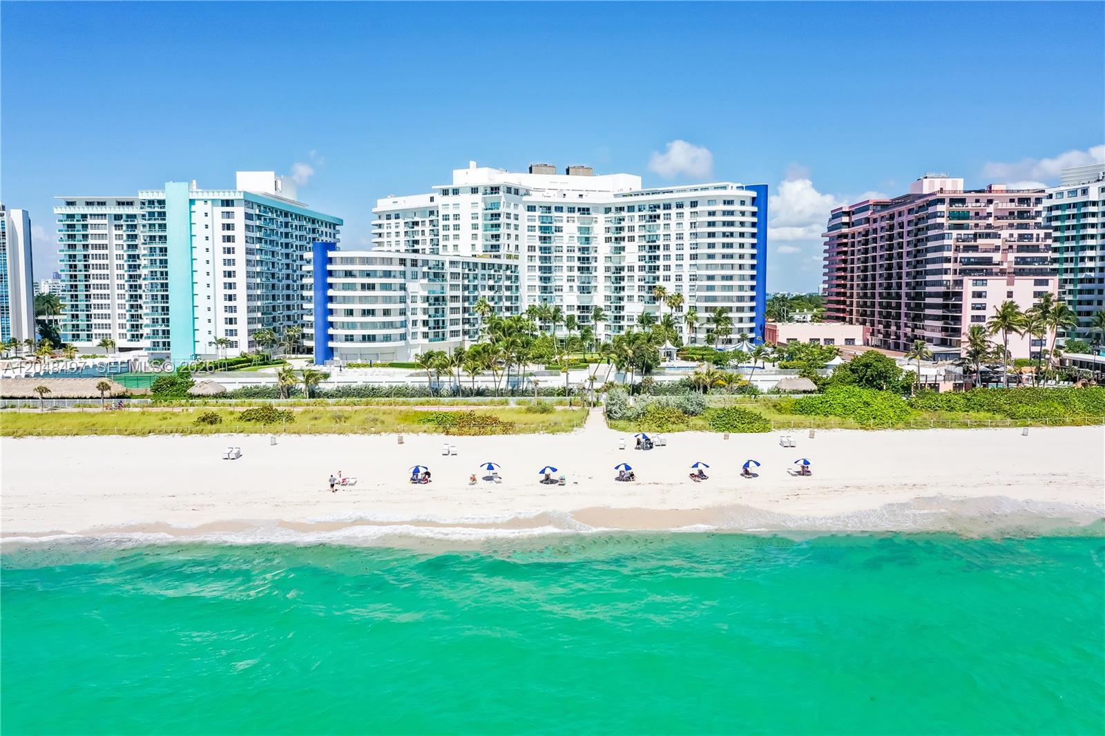 An aerial view of a sandy beach with people and umbrellas in front of large buildings — 5161 Collins Ave # 602, Miami Beach FL 33140, MIAMI BEACH, FL
