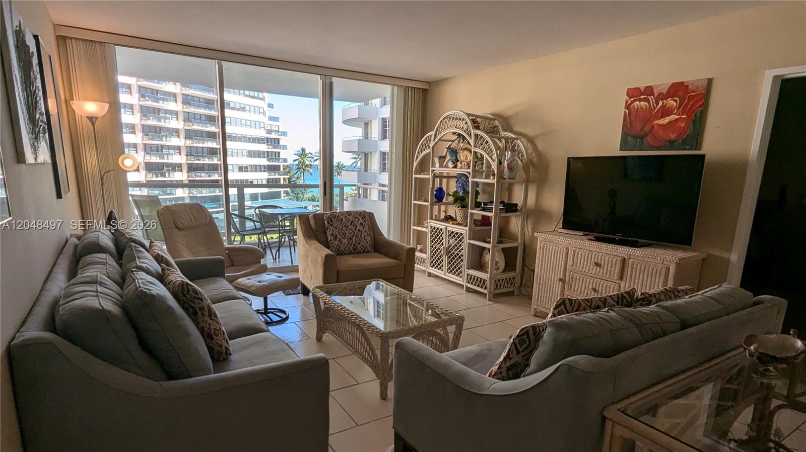 A living room features two grey sofas, a wicker coffee table, and a balcony view — 5161 Collins Ave # 602, Miami Beach FL 33140, MIAMI BEACH, FL