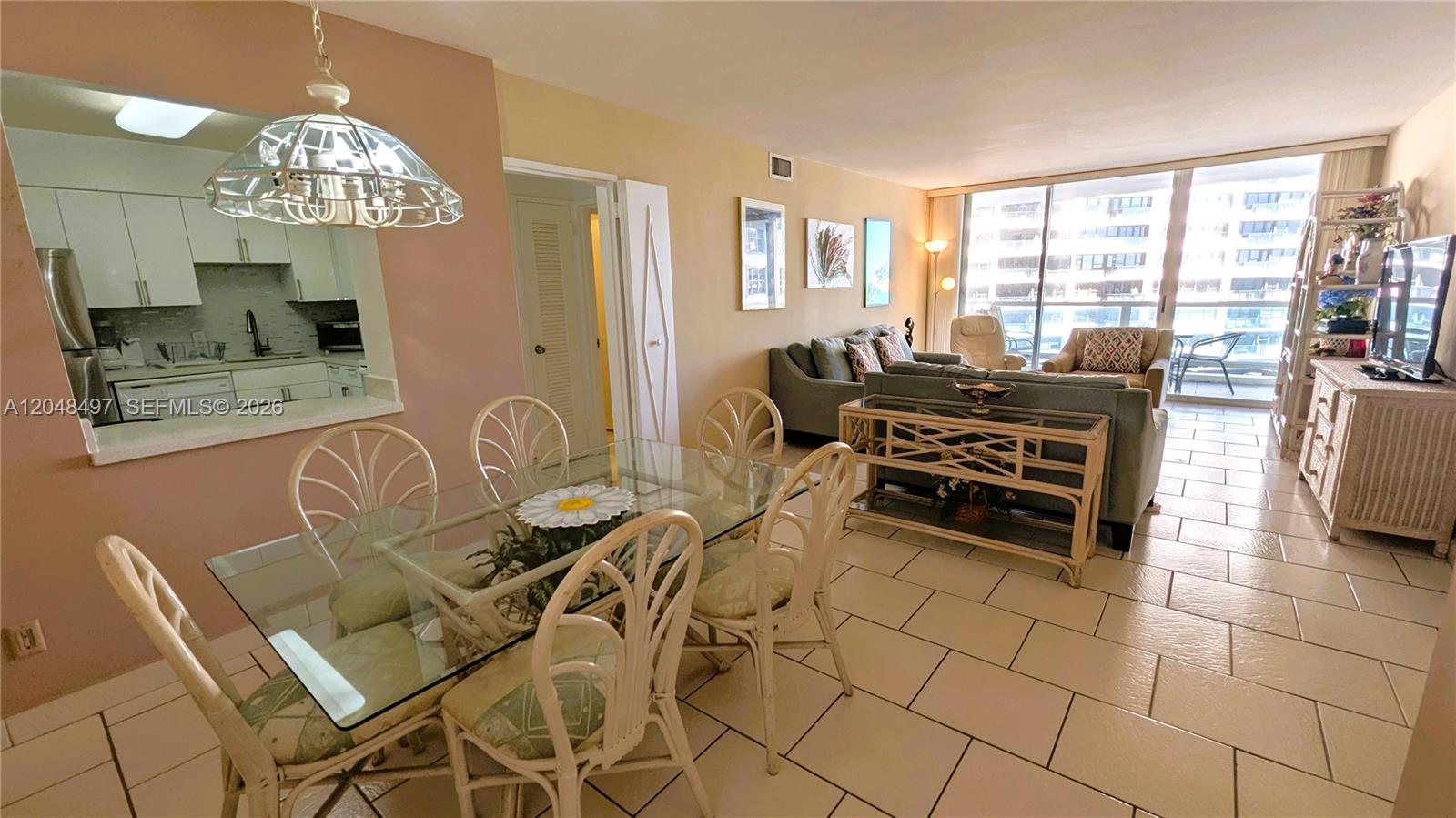 A dining area with a glass table sits adjacent to a living room with tile floors — 5161 Collins Ave # 602, Miami Beach FL 33140, MIAMI BEACH, FL