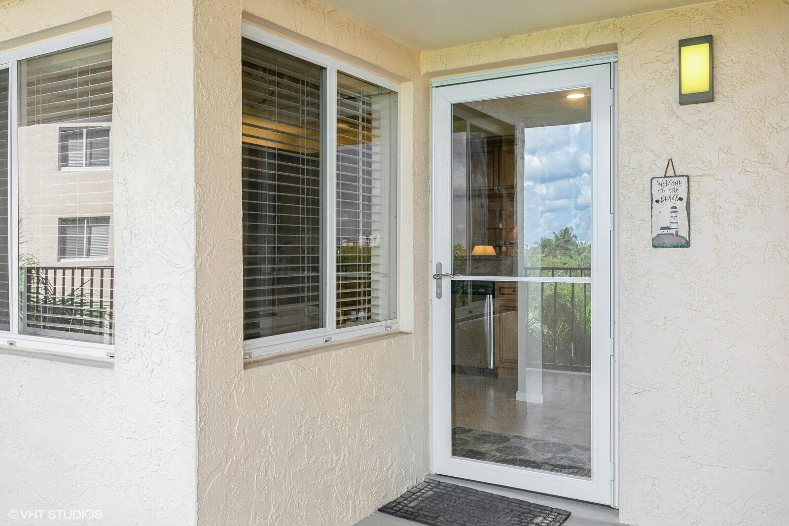 A white storm door and a window with blinds are set into a stucco wall — 275 Palm Avenue # B403, Jupiter FL 33477, JUPITER, FL