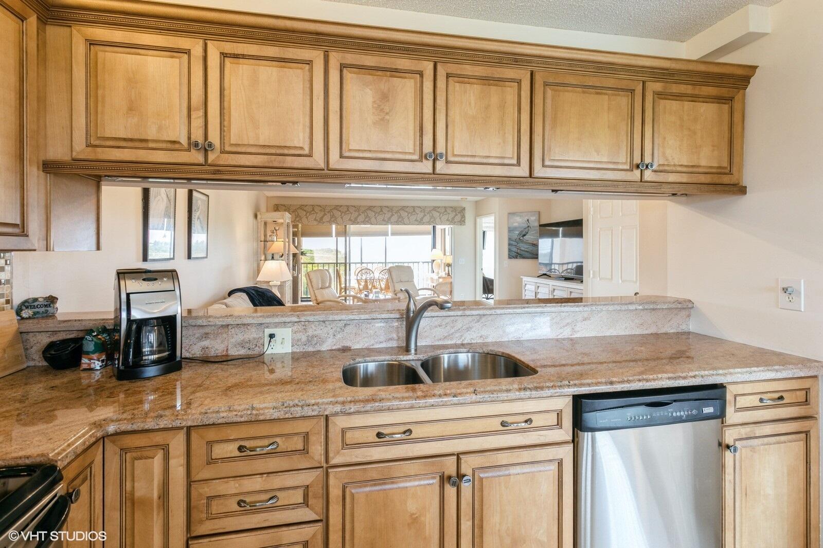 A kitchen with light wood cabinets, granite countertops, a double sink, and a pass-through window — 275 Palm Avenue # B403, Jupiter FL 33477, JUPITER, FL