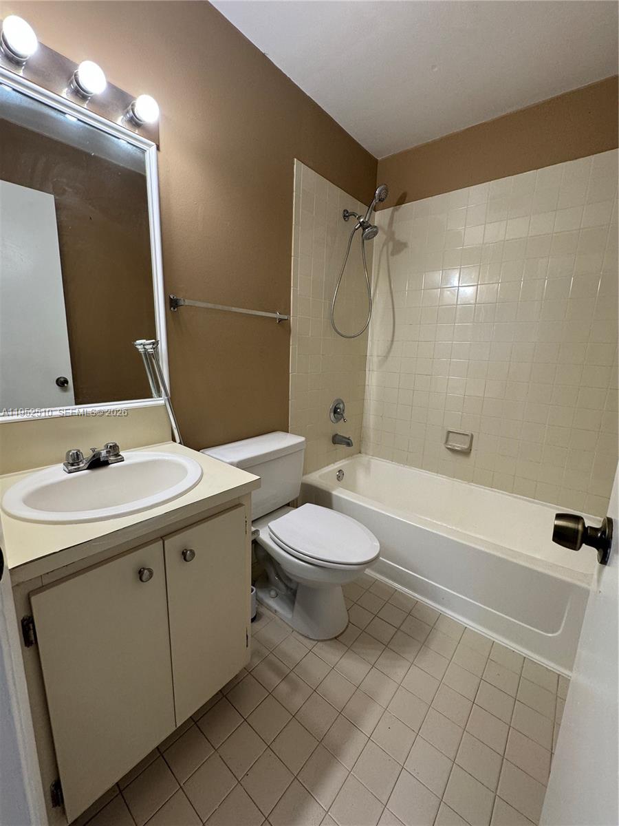 This bathroom features a vanity with a white sink, a toilet, and a tiled tub-shower — 7235 NW 179th St # 311, Hialeah FL 33015, HIALEAH, FL