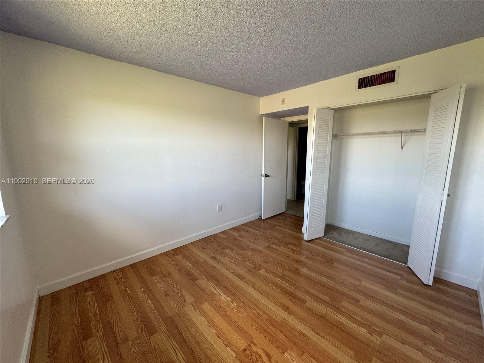 An empty bedroom features wood-look flooring, white walls, a closet, and a doorway — 7235 NW 179th St # 311, Hialeah FL 33015, HIALEAH, FL