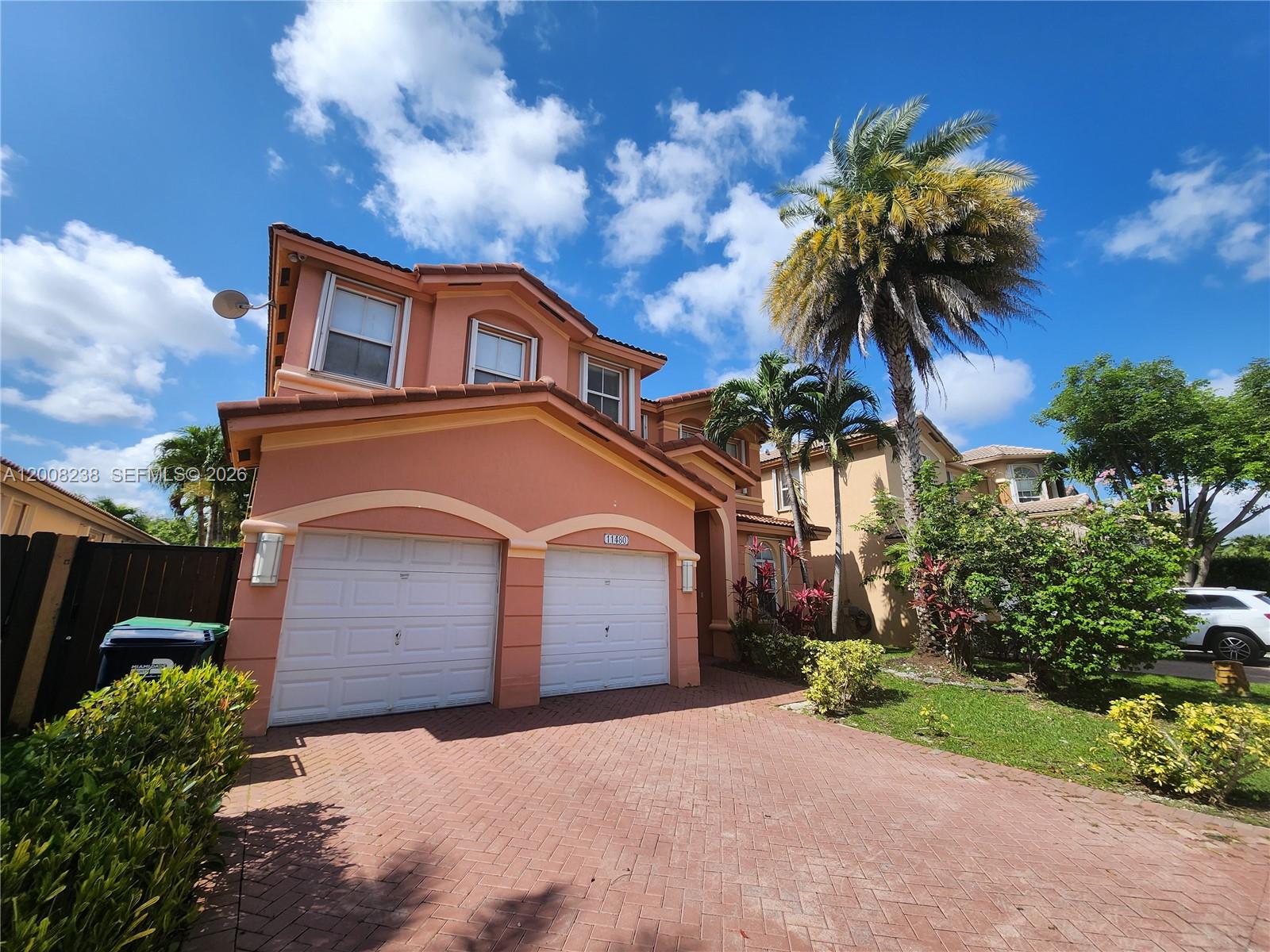 A two-story peach-colored house features a two-car garage and a brick-paved driveway — 11480 NW 82th Terrace, Doral FL 33178, DORAL, FL