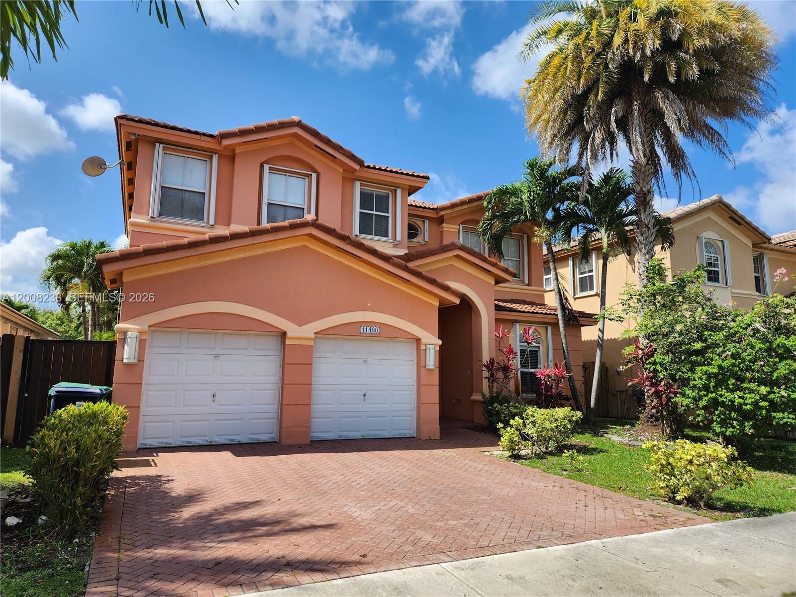 A two-story peach-colored house features a two-car garage and a brick-paved driveway — 11480 NW 82th Terrace, Doral FL 33178, DORAL, FL