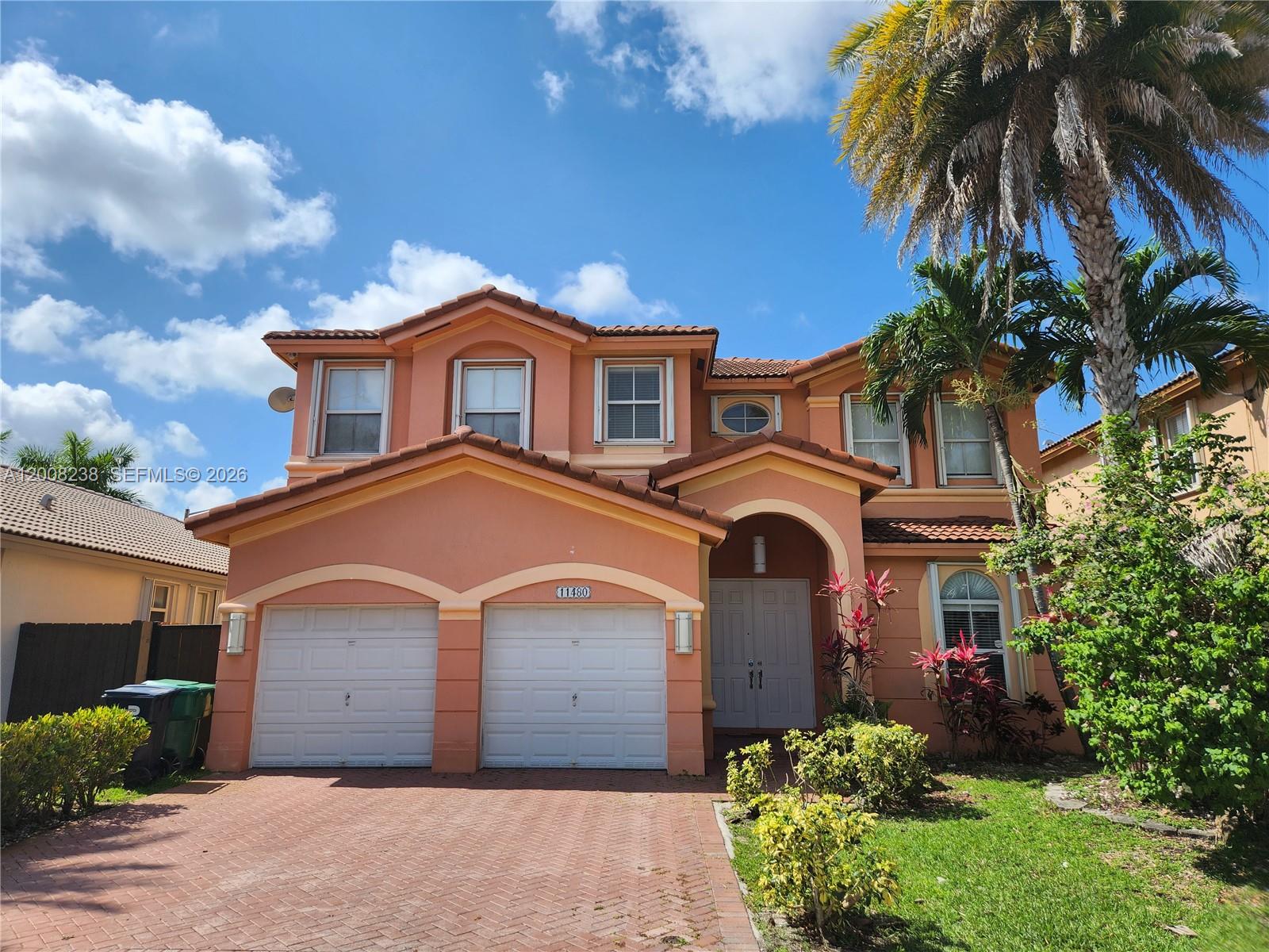 A two-story peach-colored house features a two-car garage and a brick-paved driveway — 11480 NW 82th Terrace, Doral FL 33178, DORAL, FL