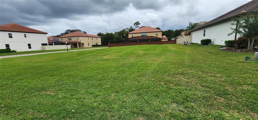 A vacant grassy residential lot is surrounded by houses under a cloudy sky — 1198 BELLA VISTA CIR, LONGWOOD, FL