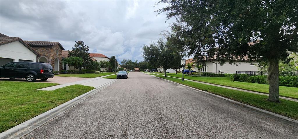A residential street features houses with tile roofs, manicured lawns, and parked vehicles — 1198 BELLA VISTA CIR, LONGWOOD, FL