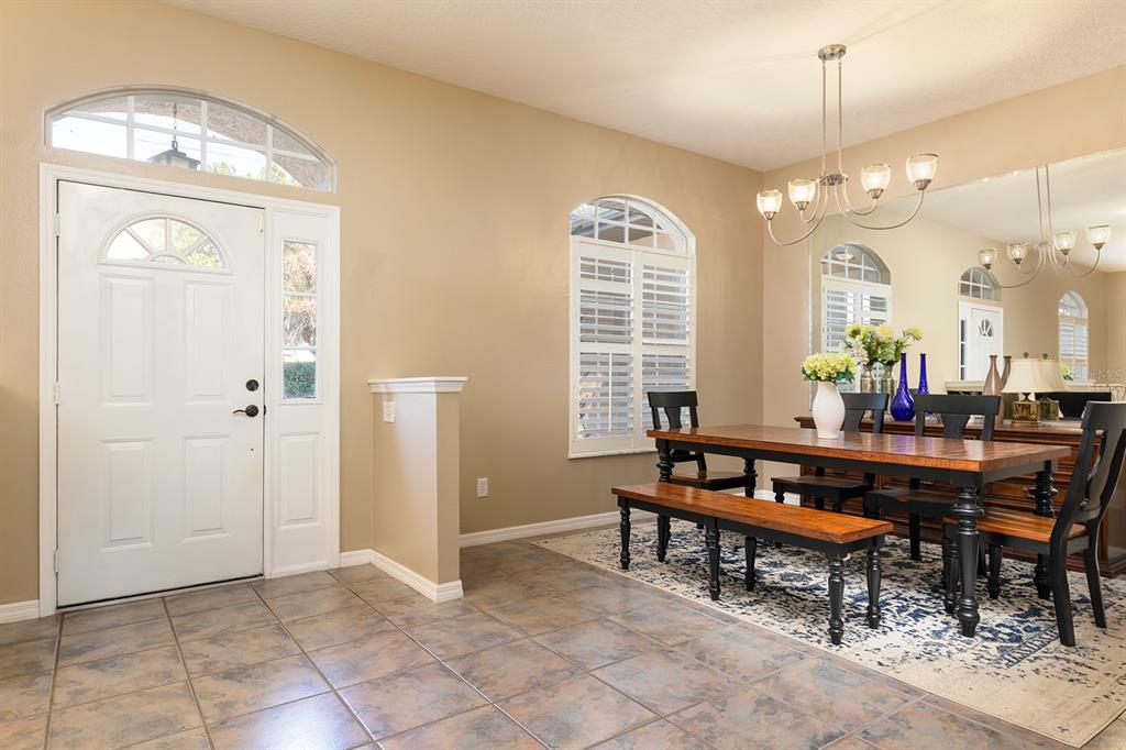 A dining room with a wooden table, bench seating, tile flooring, and a front entryway — 1357 PROVIDENCE BOULEVARD, DELTONA, FL