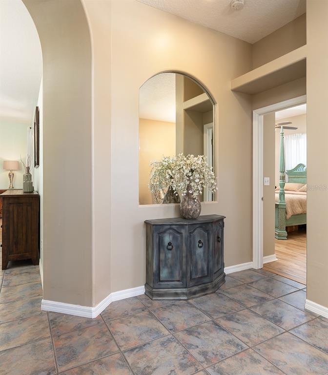An entryway features a tiled floor, an arched wall niche with a mirror, and a cabinet — 1357 PROVIDENCE BOULEVARD, DELTONA, FL