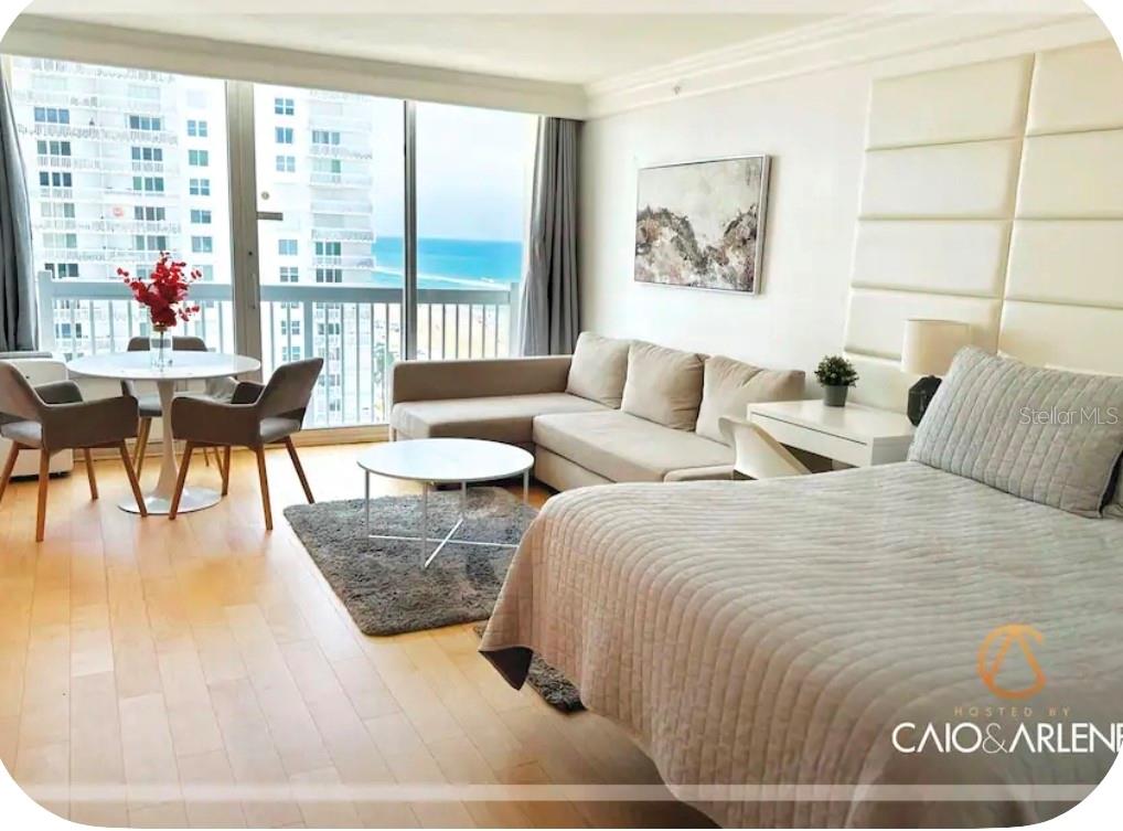 A bedroom with a seating area, ocean view, and light wood flooring — 2700 N ATLANTIC AVENUE UNIT 915, DAYTONA BEACH, FL