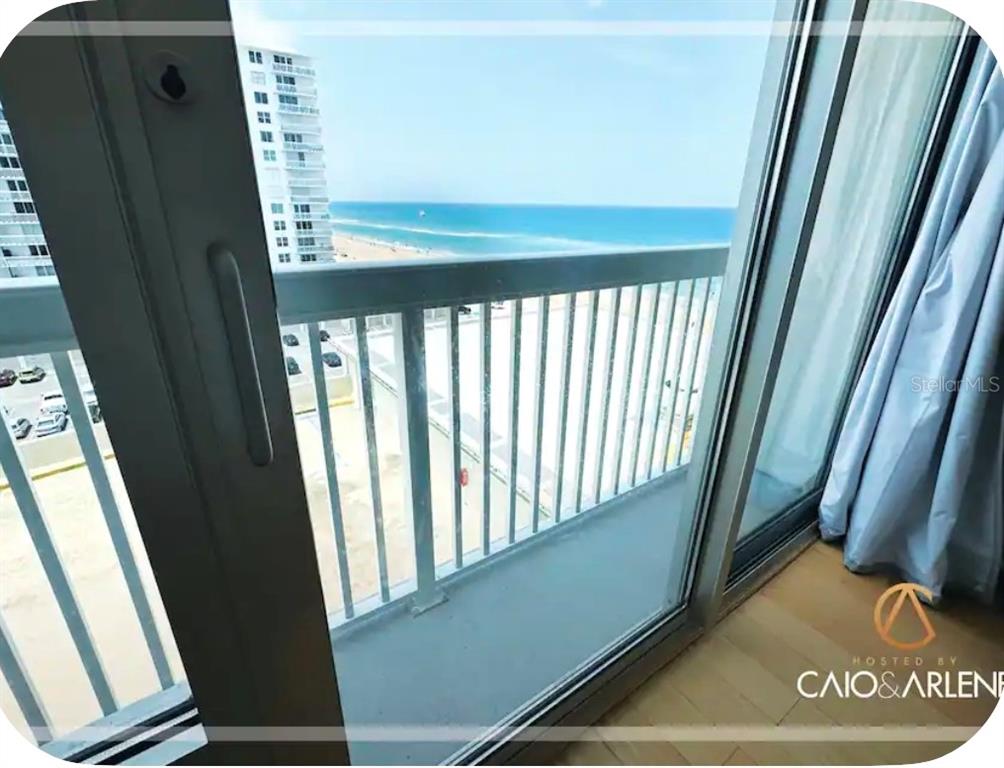 A view of the ocean and beach from a balcony through a sliding glass door — 2700 N ATLANTIC AVENUE UNIT 915, DAYTONA BEACH, FL