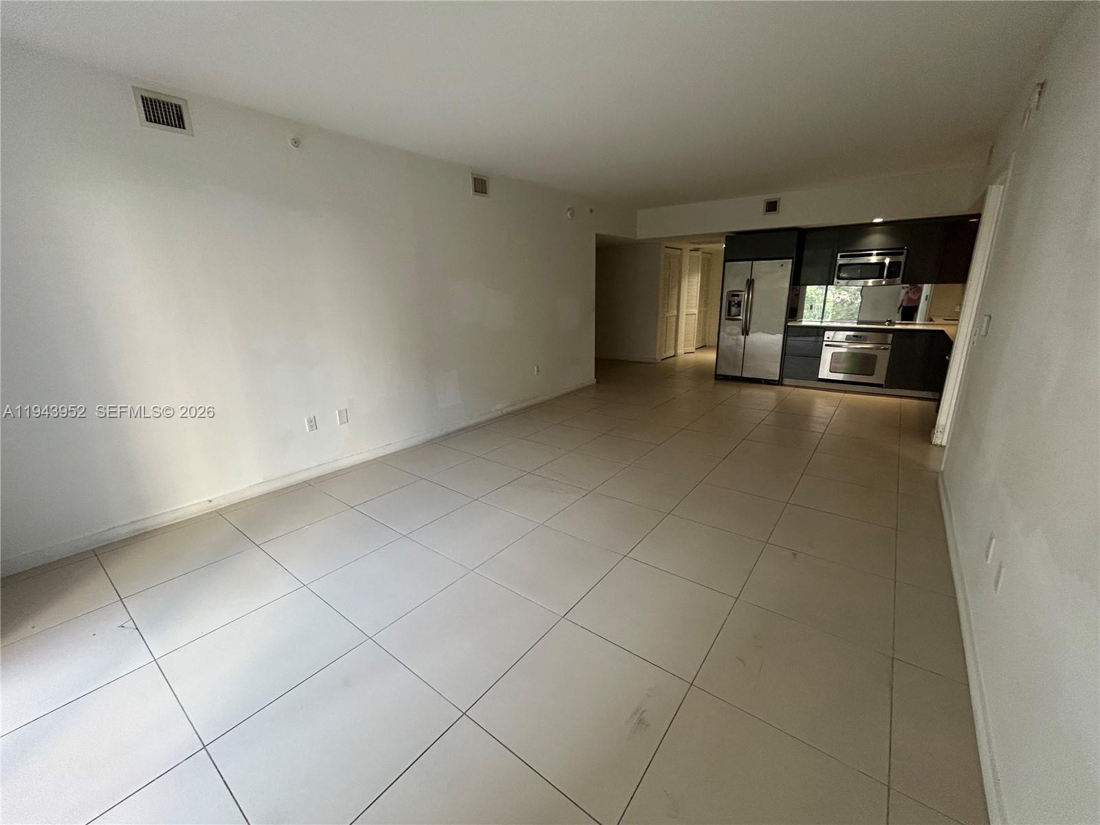 An open-concept living area features white walls, light tile flooring, and a modern kitchen — 31 SE 6th St # 407, Miami FL 33131, MIAMI, FL