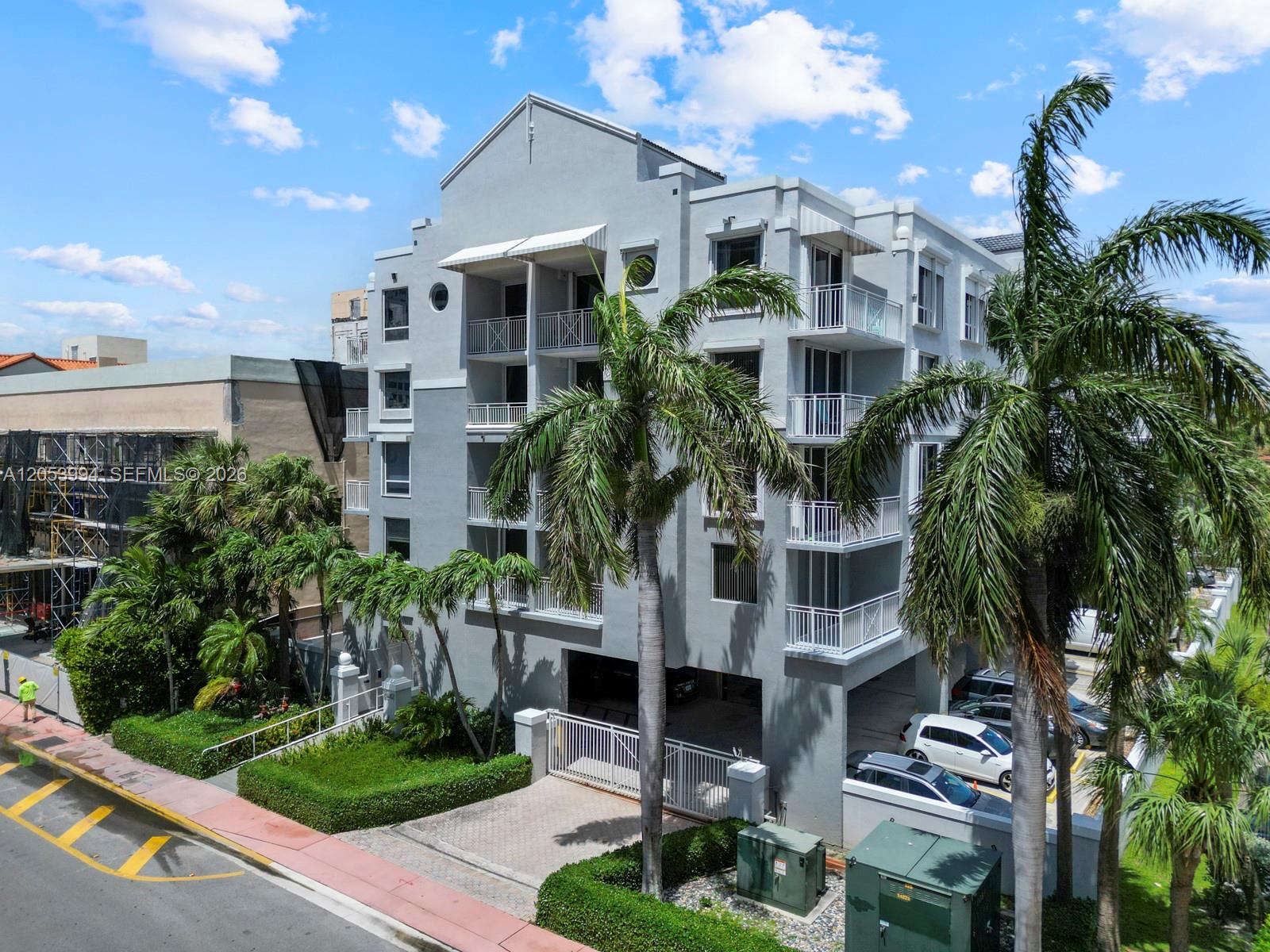 An exterior view of a multi-story gray apartment building with balconies and palm trees — 2642 Collins Ave # 303, Miami Beach FL 33140, MIAMI BEACH, FL