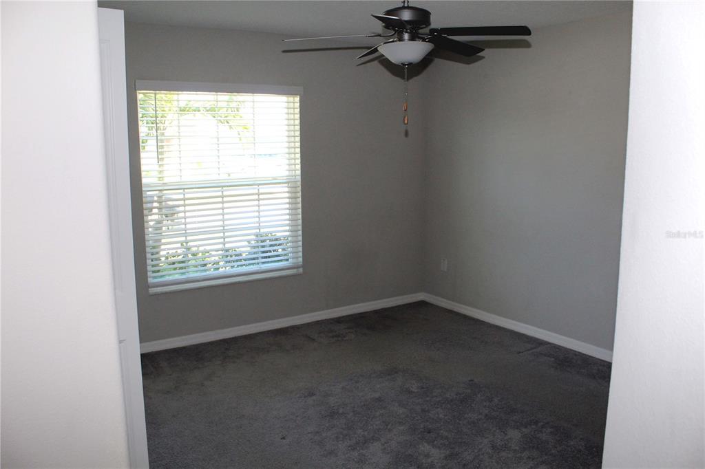 An empty bedroom features gray carpet, light gray walls, and a ceiling fan — 17152 SUNSHINE MIMOSA STREET, WIMAUMA, FL